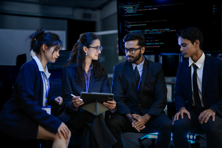 A development team participates in a project debriefing in a corporate command center They are analyzing post launch metrics and discussing the next development sprint and strategy