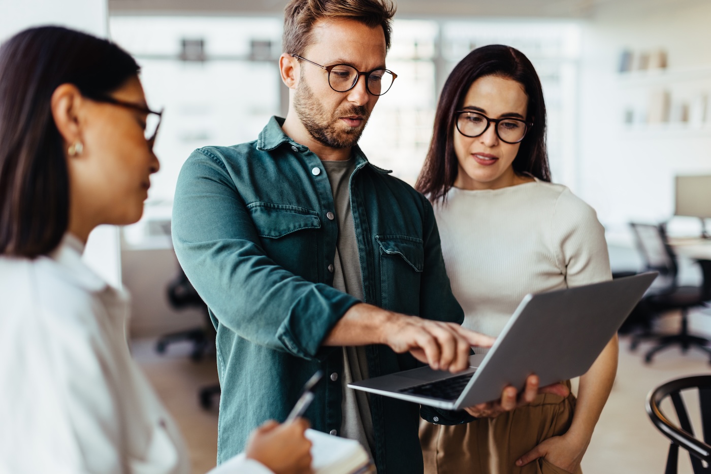 Group of business people using a laptop and having a discussion in an office. Team of business professionals standing together and having a meeting.