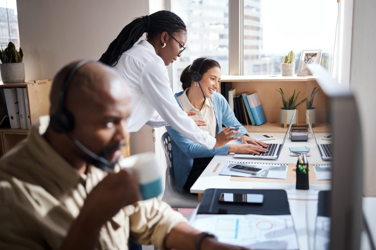 Shot of two businesswomen using a headset and computer while working in a modern office