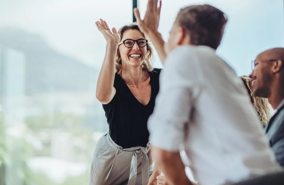 Businesswoman giving a high five to male colleague in meeting. Business professionals high five during a meeting in boardroom.