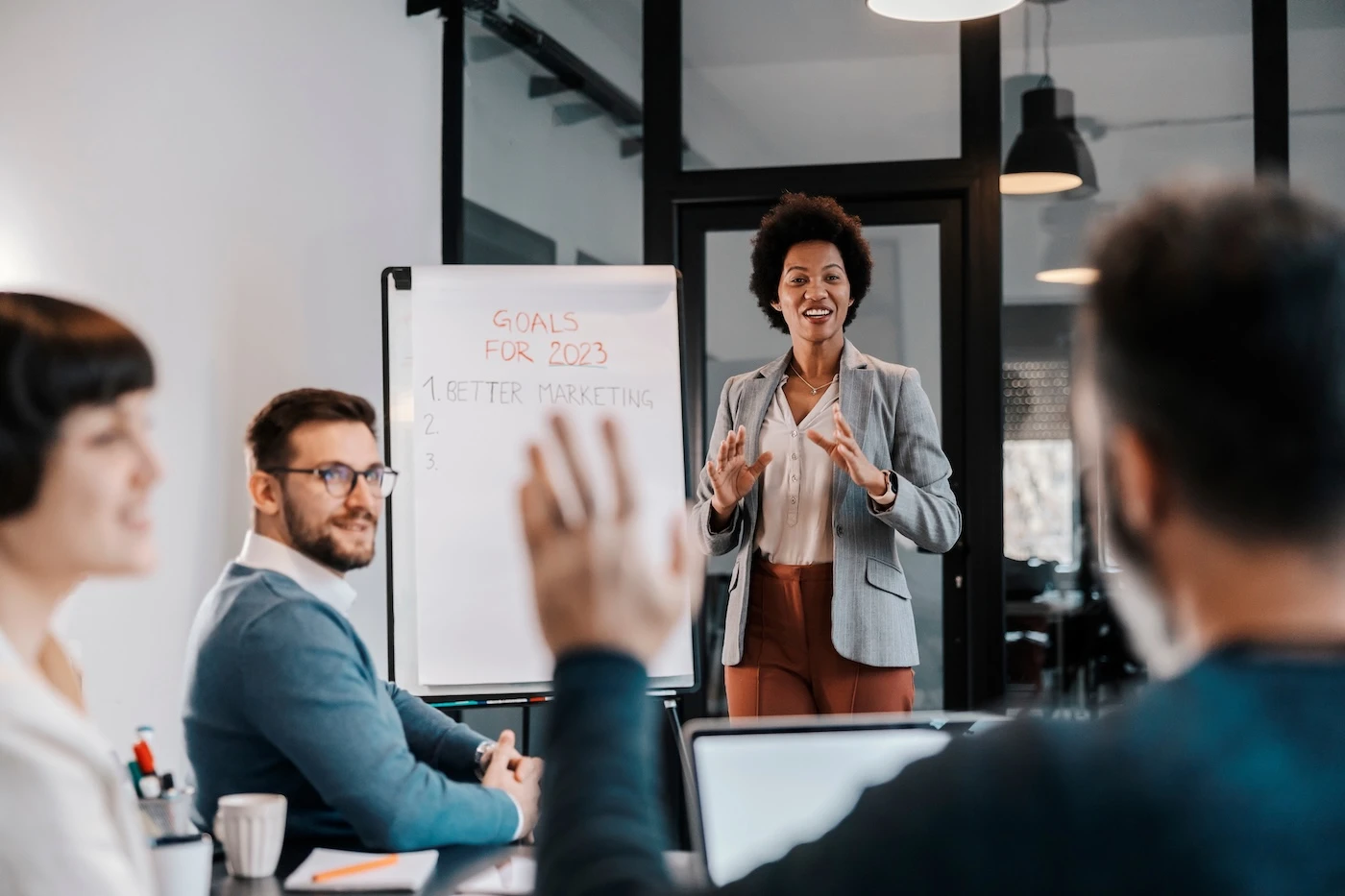 A interracial businesswoman is standing at the office with her team and brainstorming ideas for project.