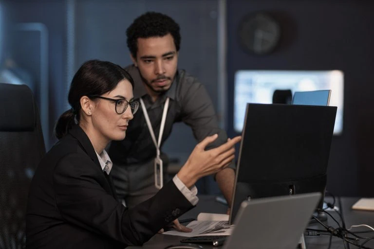 Senior project manager pointing at computer screen while reviewing code