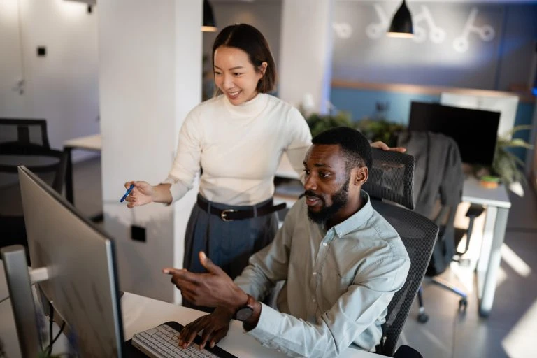 Diverse colleagues collaborating on computer in modern office